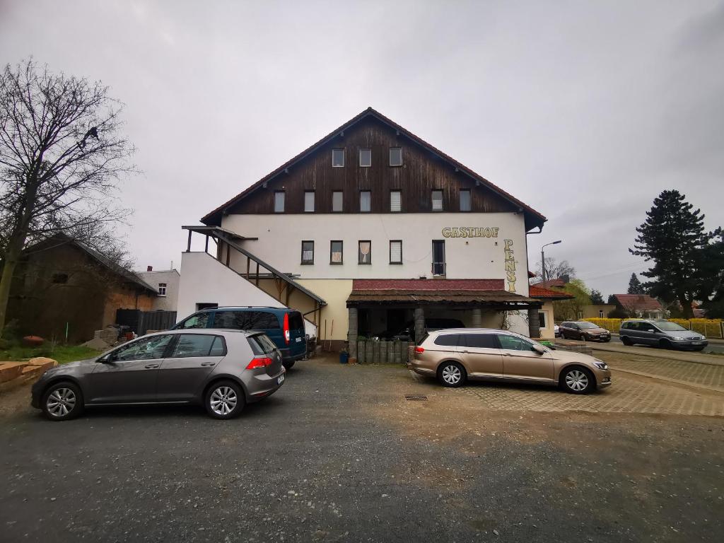 zwei Autos auf einem Parkplatz vor einem Gebäude geparkt in der Unterkunft Pension Bremer in Lindenthal
