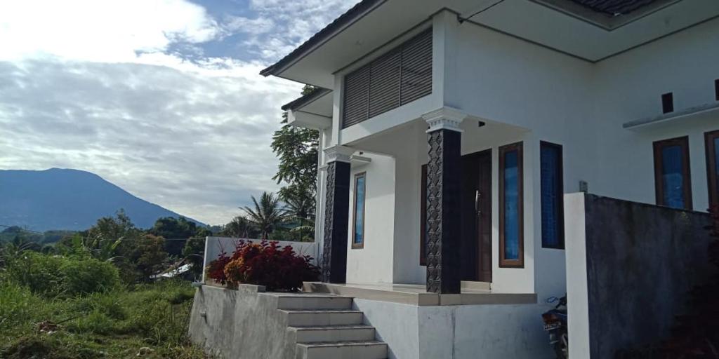 a white house with stairs and a mountain in the background at Villa SINGGALANG Syariah in Padangluar