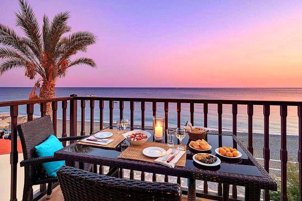 een tafel met eten op een balkon met uitzicht op het strand bij Myrtos Mare Suites in Myrtos