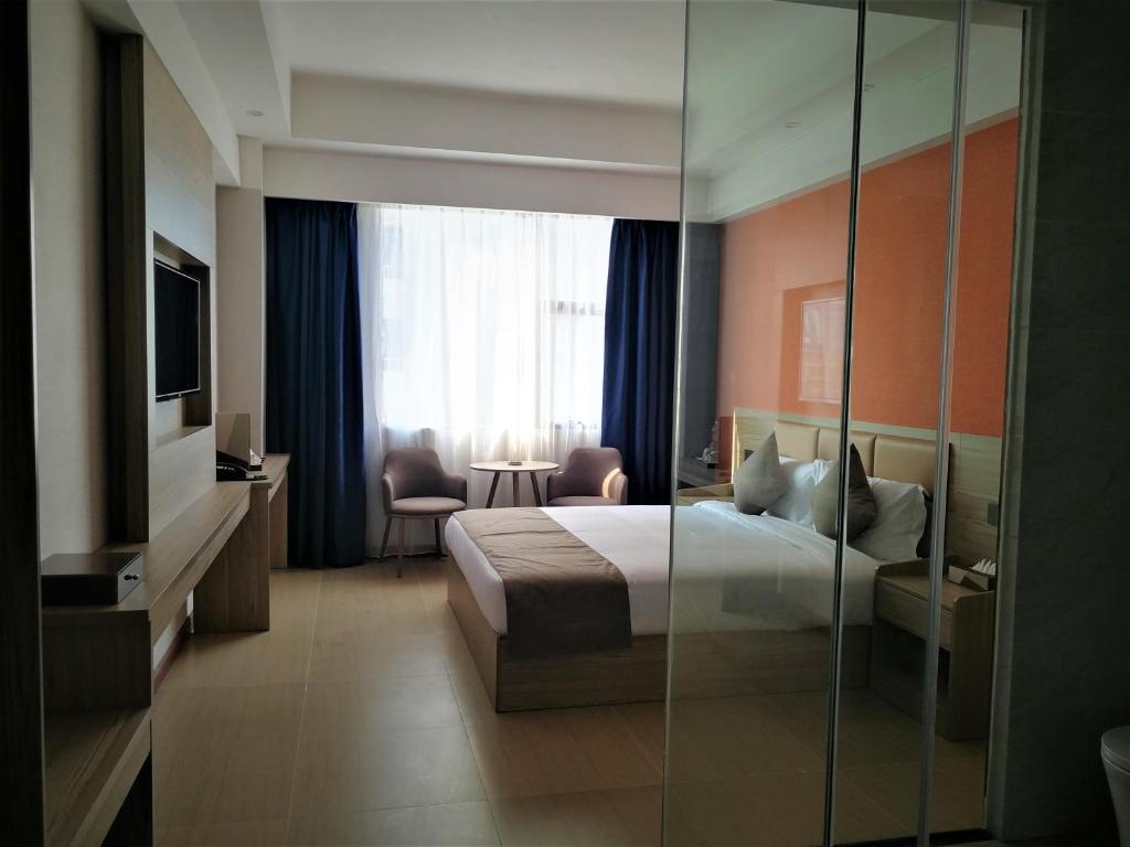 PACI Hotel&SPA في سيهانوكفيل: غرفة فندق بسرير وجدار زجاجي