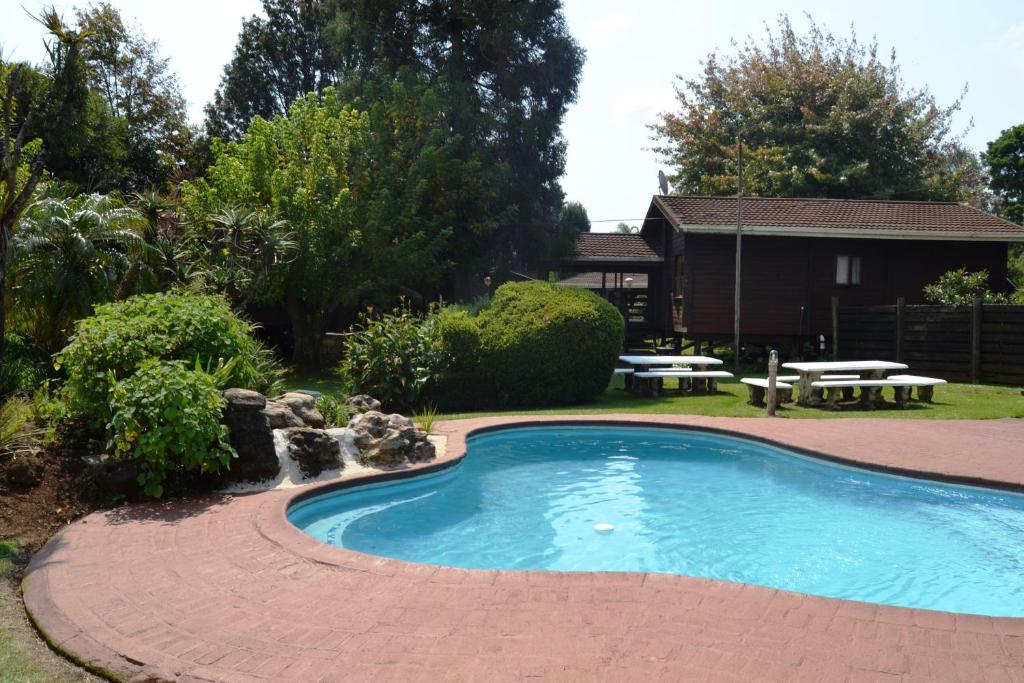 una piscina en un patio con mesa y bancos en Log Cabin & Settlers Village en Graskop