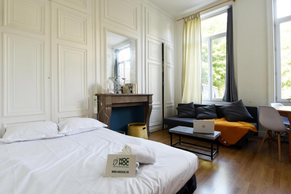 NOCNOC - Le Petit National في ليل: غرفة نوم بيضاء مع سرير وأريكة