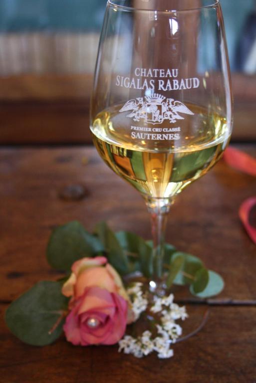 a glass of white wine and flowers on a table at Château Sigalas Rabaud in Bommes