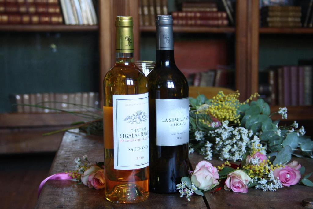 two bottles of wine sitting on a table with flowers at Château Sigalas Rabaud in Bommes