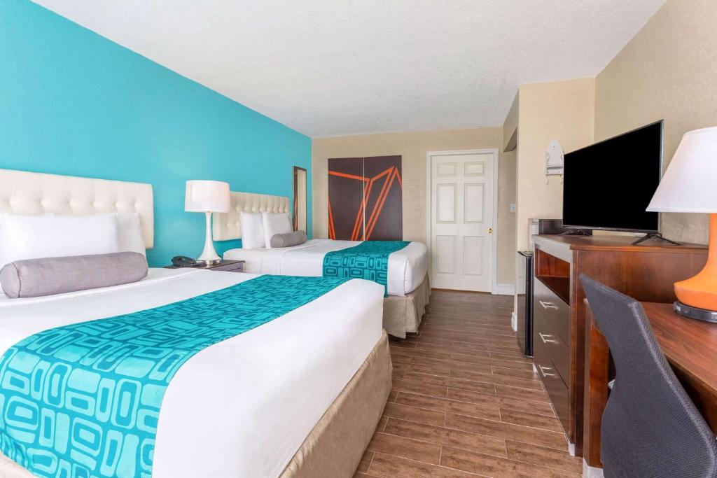 a hotel room with two beds and a flat screen tv at Howard Johnson by Wyndham Lakeland in Lakeland