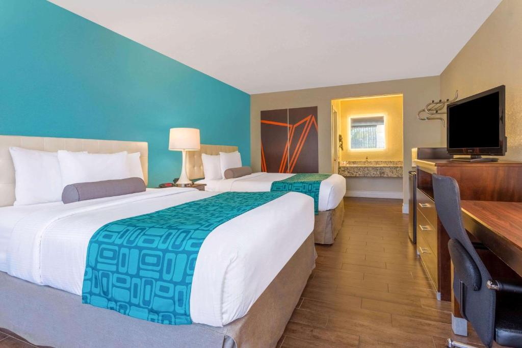 a hotel room with two beds and a flat screen tv at Howard Johnson by Wyndham Lakeland in Lakeland