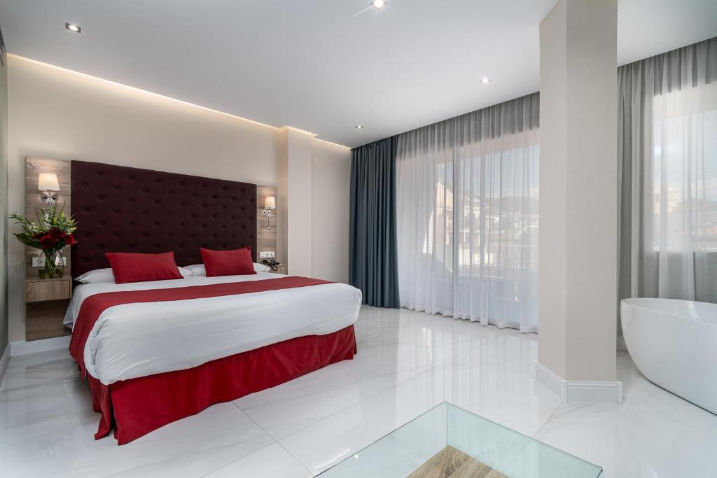 a bedroom with a large bed and a bath tub at Los Arcos in Nerja