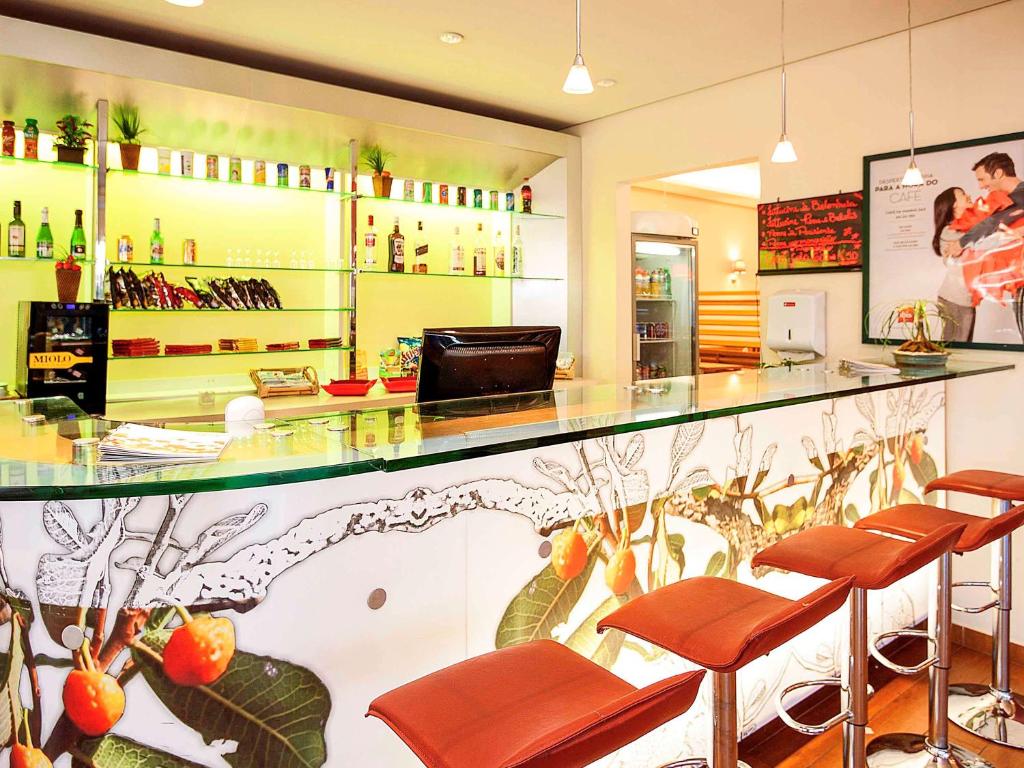 a restaurant with a bar with brown leather stools at ibis Uberlandia in Uberlândia