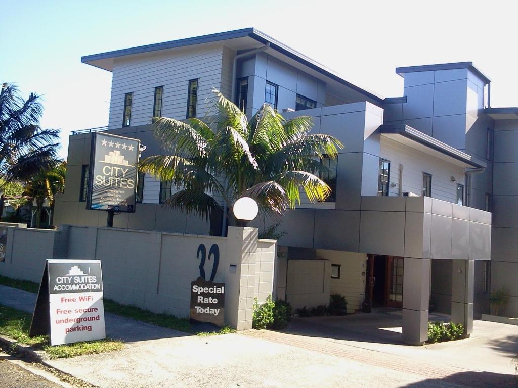 un edificio con una palmera delante de él en City Suites, en Tauranga