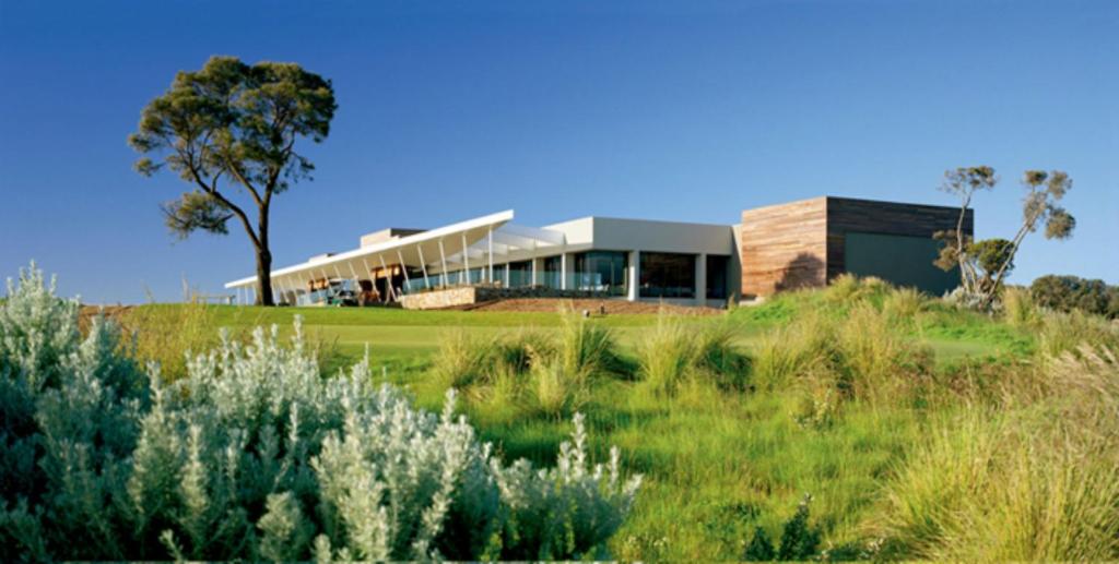 a house on top of a hill with a grass field at Peppers Moonah Links Resort in Fingal