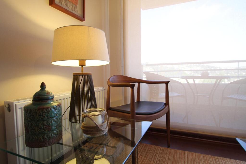 una mesa de cristal con una silla y una lámpara en Alto Sporting Apartments, en Viña del Mar