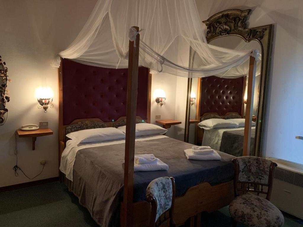 a bedroom with a canopy bed and a large mirror at Hotel Ficocle in Cervia
