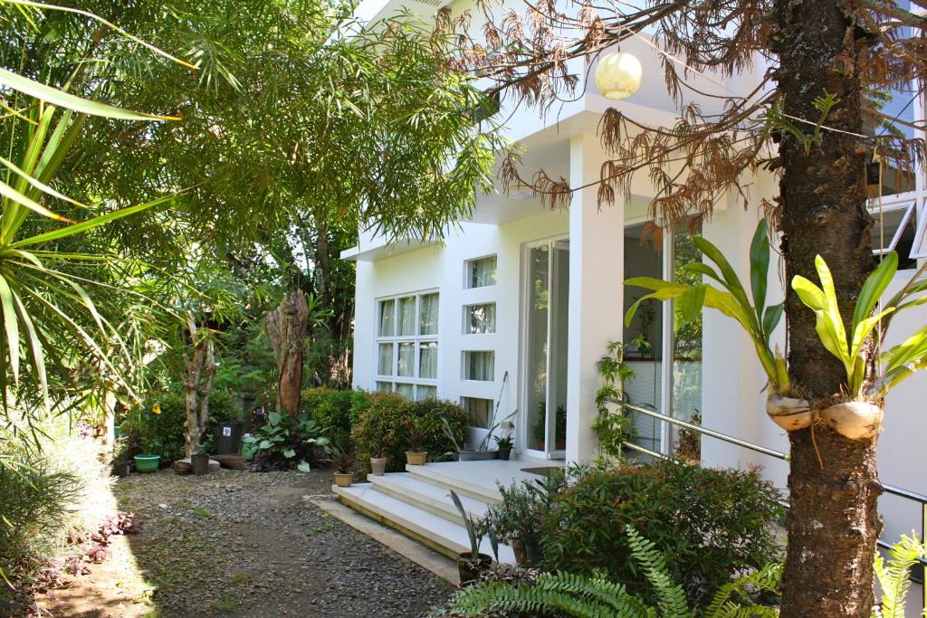 une maison blanche avec des arbres et des plantes dans l'établissement Greenspace Palawan, à Puerto Princesa