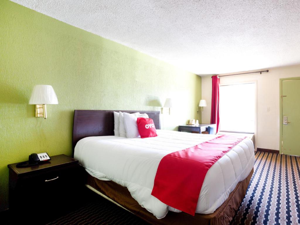 a hotel room with a large bed with red pillows at OYO Hotel Pensacola I-10 & Hwy 29 in Pensacola