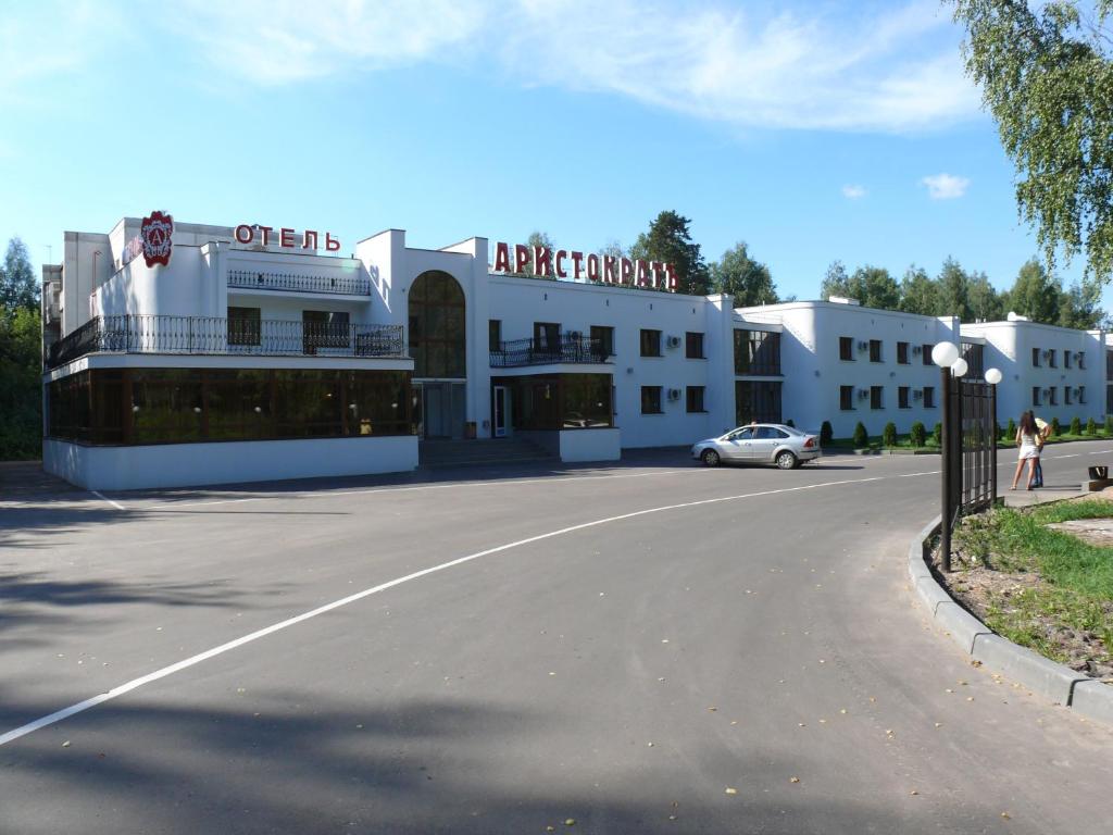 a large white building with a car parked on the street at Hotel Aristokrat Kostroma in Kostroma