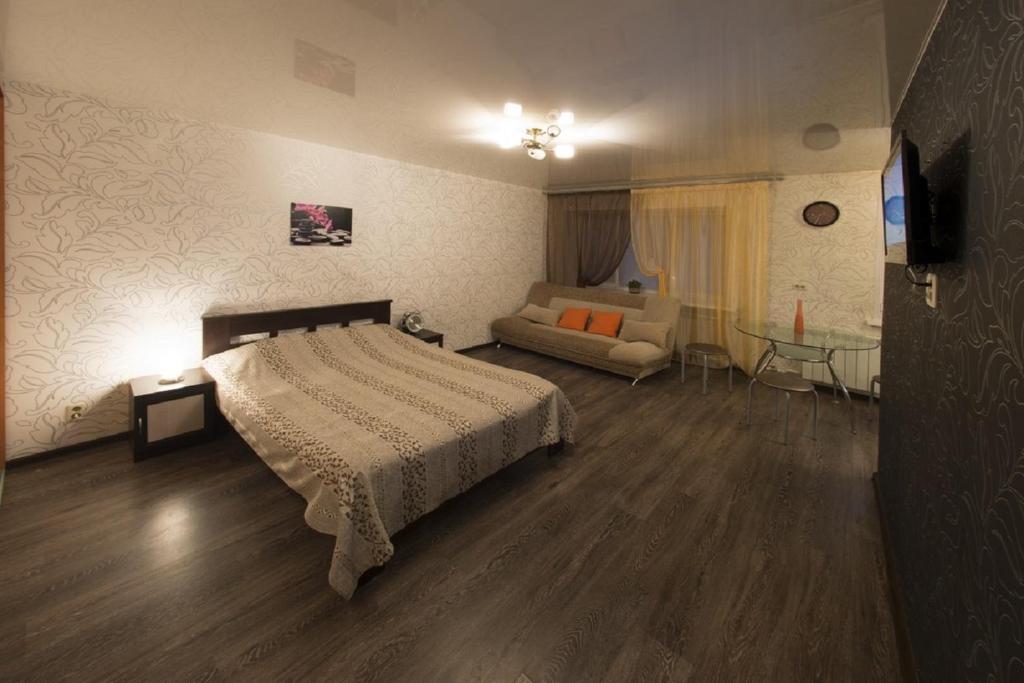 ヤロスラヴリにあるApartments on Uglichskaya 31のベッドルーム1室(ベッド1台、ソファ、テーブル付)