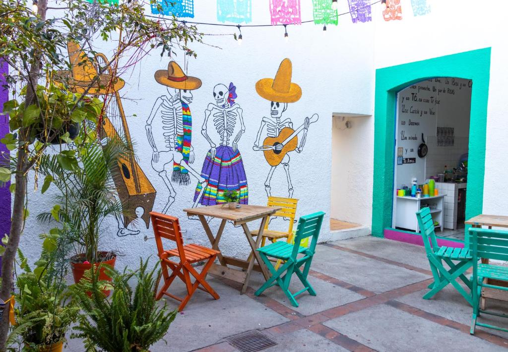 une table et des chaises devant un mur orné d'une fresque murale dans l'établissement Hostal Casa Colores Adults Only, à Guadalajara