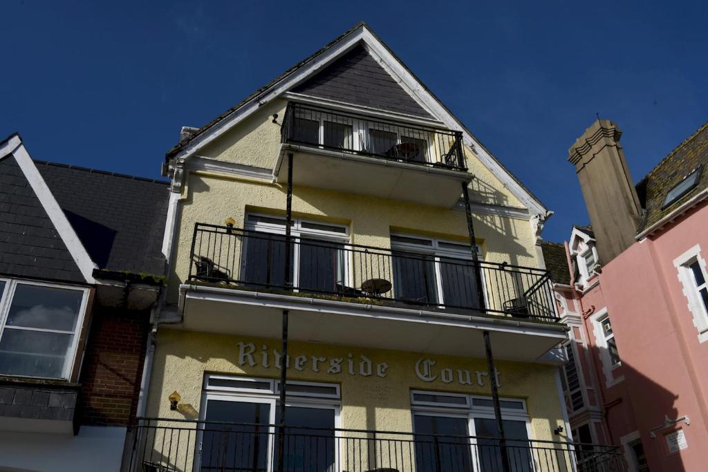 a yellow building with a balcony on top of it at Riverside 2 in Dartmouth