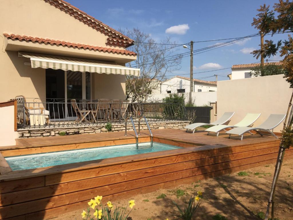 a backyard with a swimming pool and a wooden deck at Villa Caramel in Saint-Quentin-la-Poterie