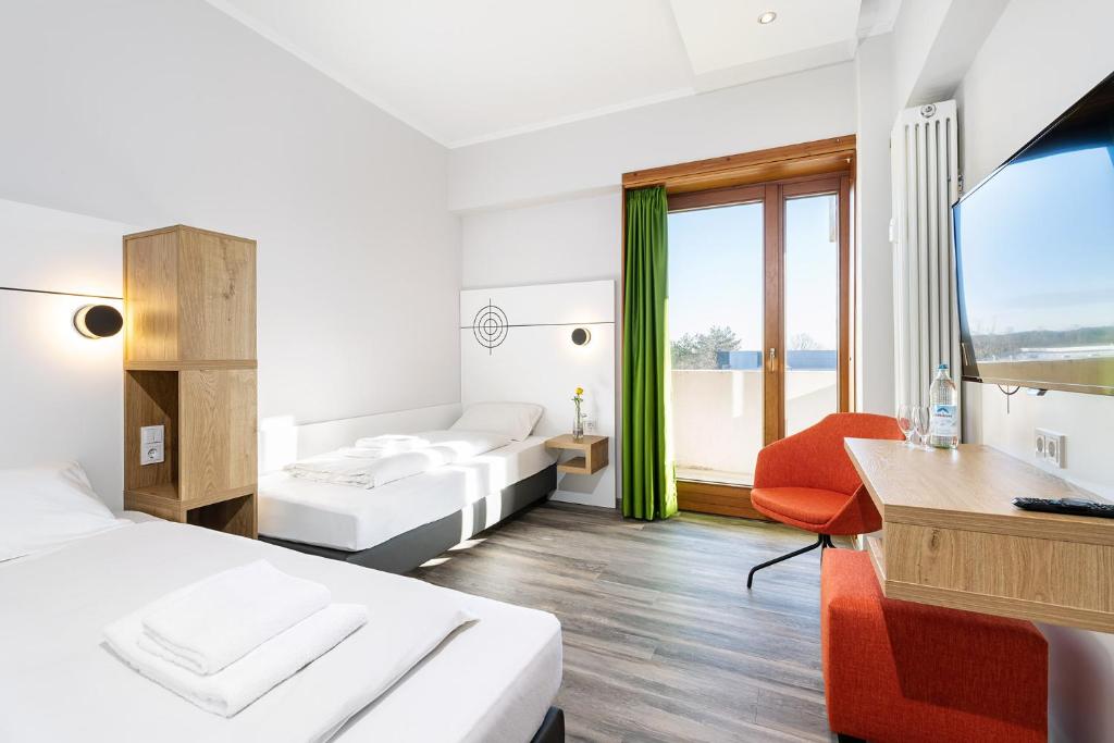 a hotel room with two beds and a desk at Hotel Olympia Schießanlage in Garching bei München