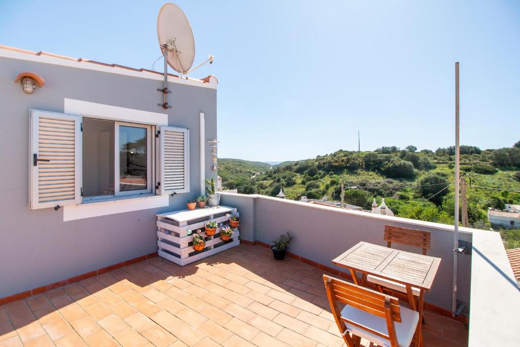 einen Balkon eines Hauses mit einem Tisch und einem Fenster in der Unterkunft Casa Oceano-Mar a vista in Raposeira
