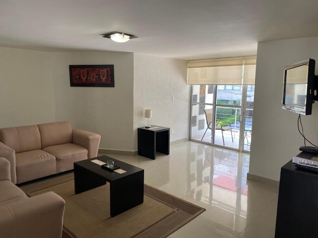 a living room with a couch and a tv at Grupo Kings Suites - Monte Chimborazo 567 in Mexico City