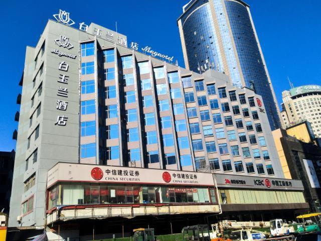 Magnotel guiyang fountain commercial center subway station hotel في غوييانغ: مبنى كبير في مدينة ذات مباني طويلة