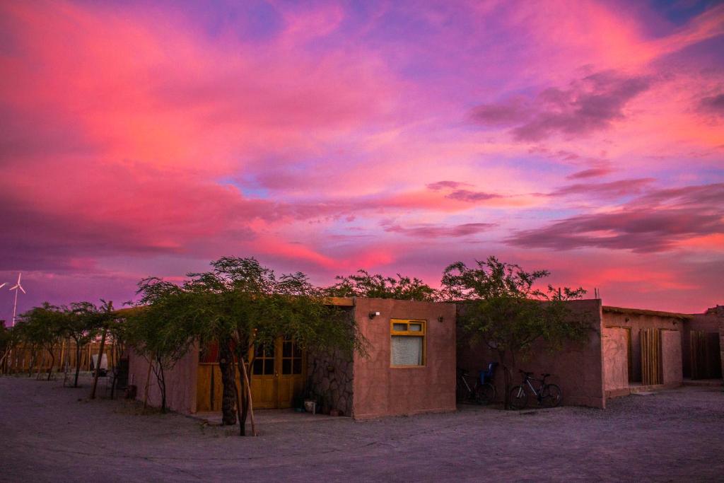 una puesta de sol sobre un edificio en el desierto en Sol del Desierto, en Chíuchíu