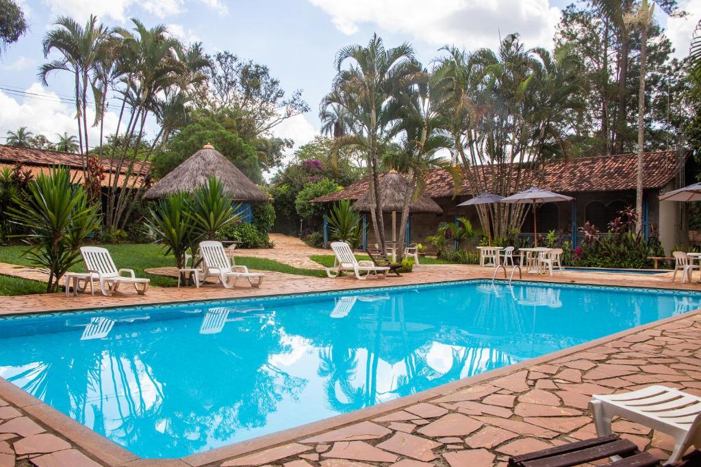 einen Pool in einem Resort mit Stühlen und Sonnenschirmen in der Unterkunft Pousada Villa da Serra in Brumadinho