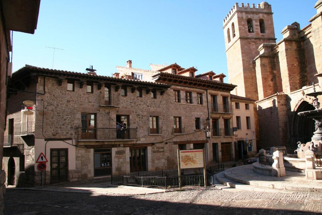 an old stone building with a clock tower in a street at Apartamentos La Iglesia in Mora de Rubielos