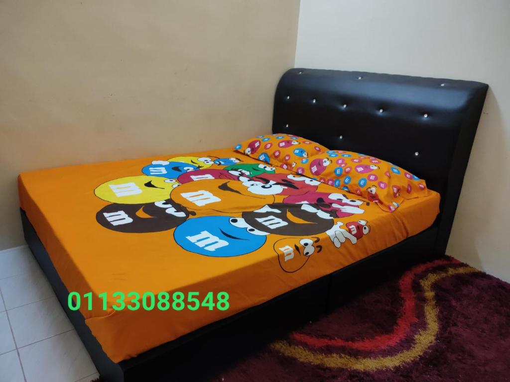 een bed met een dekbed met tekenfilms erop bij Homestay Tengku Maheran in Jitra