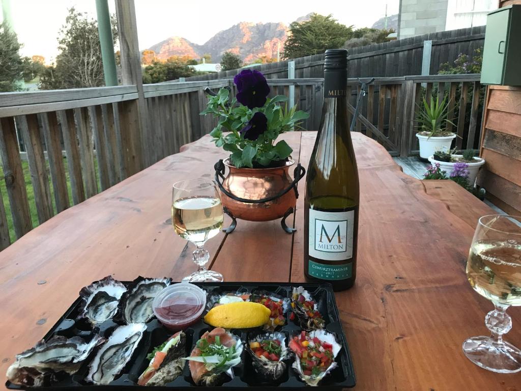 a table with a bottle of wine and a plate of fish at Gumnut Cottage in Coles Bay