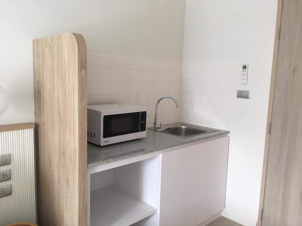 A compact kitchenette with a microwave, sink and under-counter storage beside the bedroom.