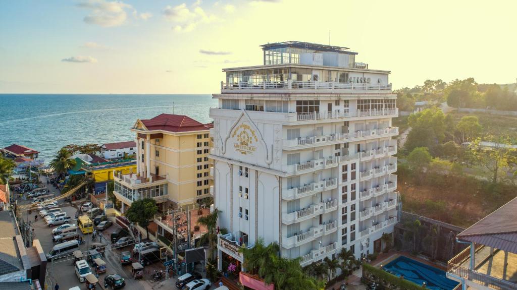 a tall white building with a clock on it next to the ocean at Aristocrat Residence & Hotel in Sihanoukville