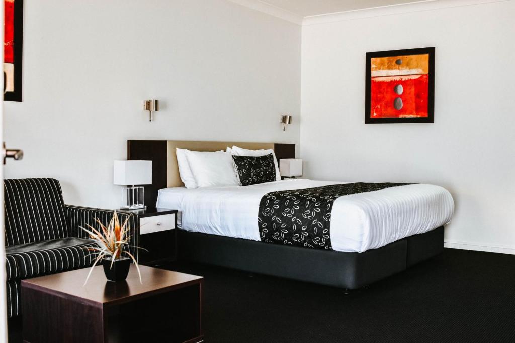 a hotel room with a bed and a chair at The Charles Boutique Hotel & Dining in Wagga Wagga