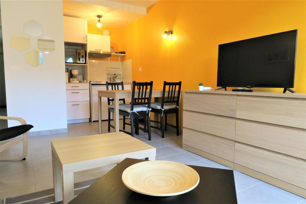 un salon avec une télévision et une table avec des chaises dans l'établissement Bel Appartement neuf 2 à 4 pers à 100m de la plage à PERROS-GUIREC - Réf 856, à Perros-Guirec