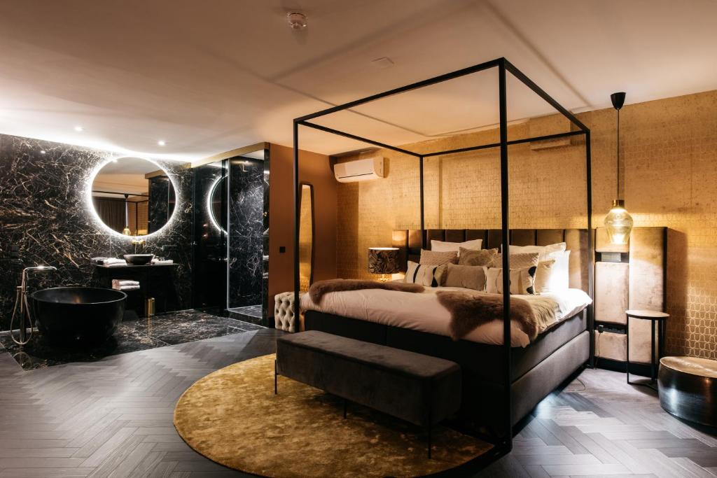 una camera con letto a baldacchino e vasca da bagno di Hotel Britannique a Maastricht