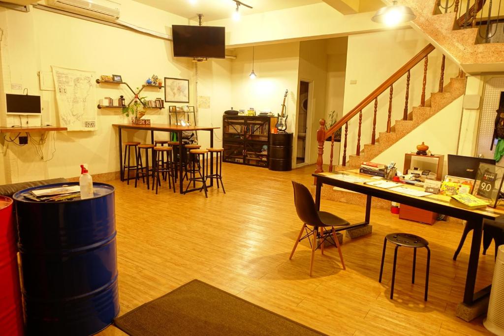 a living room with a table and chairs and a staircase at Chiayi Petite Hostel in Chiayi City