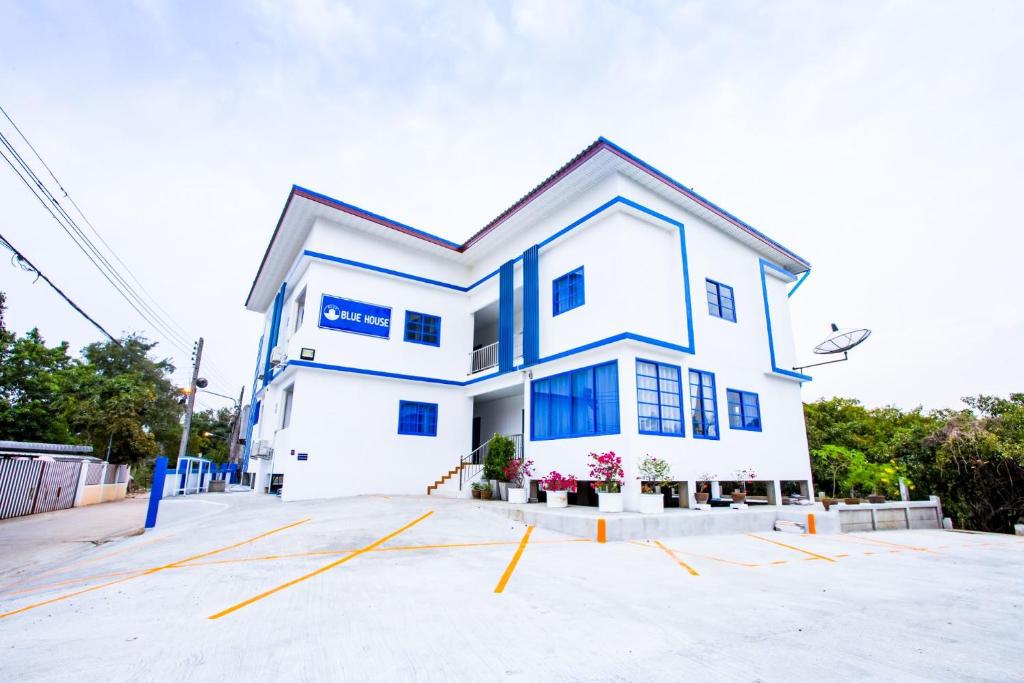 a white house with blue windows in a parking lot at Blue House in Ang Thong