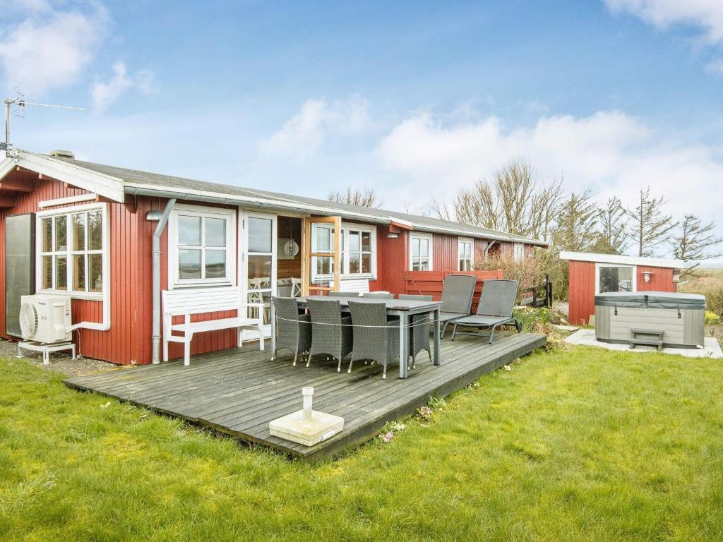 uma casa vermelha com um deque e um grelhador em 6 person holiday home in Lemvig em Lemvig