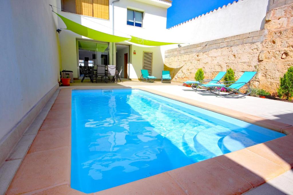 une piscine avec des chaises bleues et un bâtiment dans l'établissement Casa Foners Mallorquins 004 by Mallorca Charme, à Muro