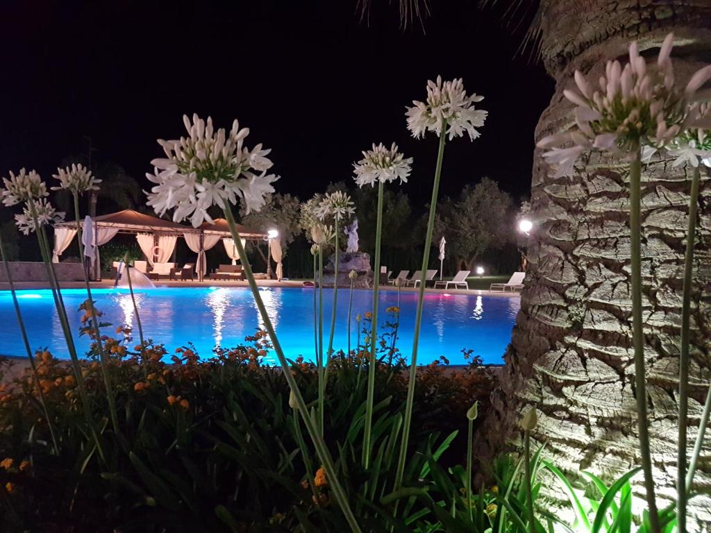 una piscina por la noche con flores blancas en Agriturismo La Fattoria, en Otranto