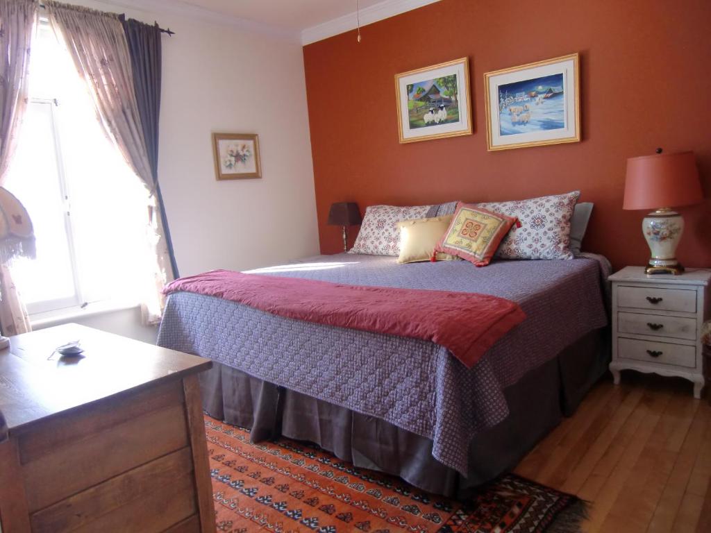 a bedroom with a bed and a dresser and a window at Auberge de Lotbinière in Lotbinière