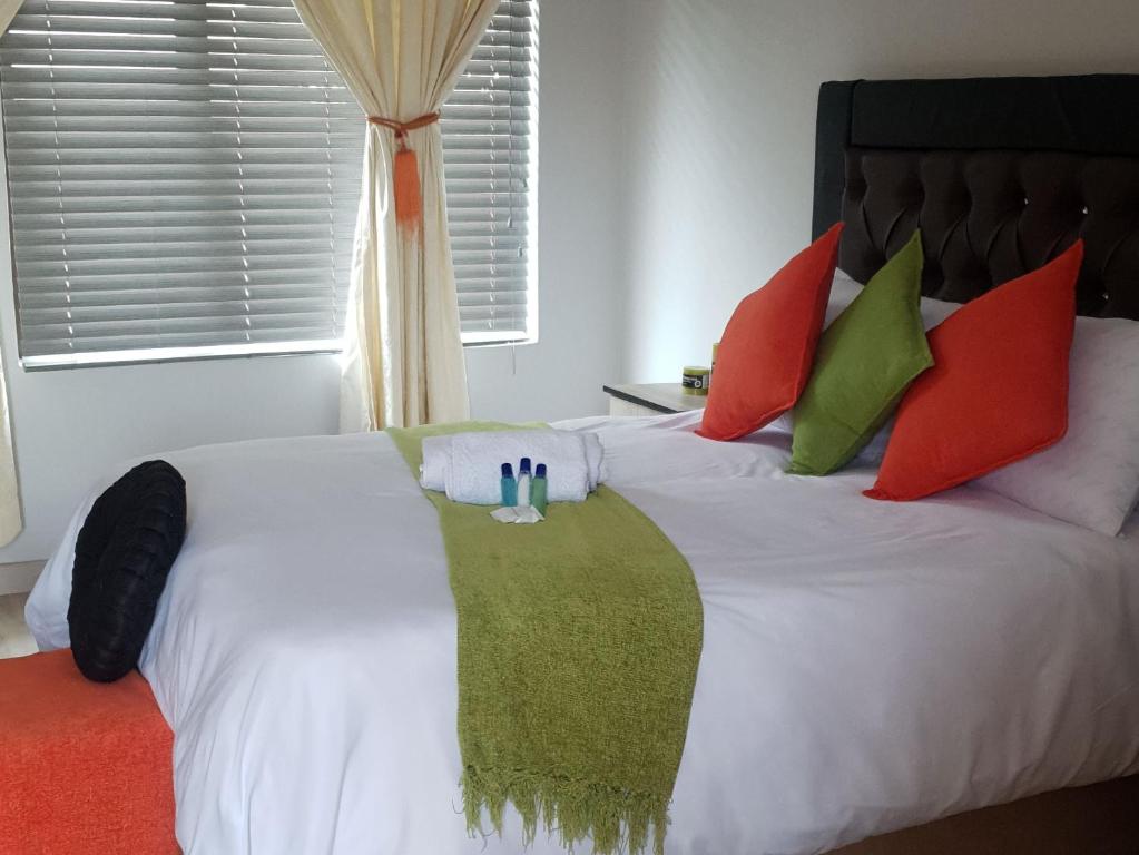a bedroom with a white bed with red and green pillows at Vaticious in Secunda