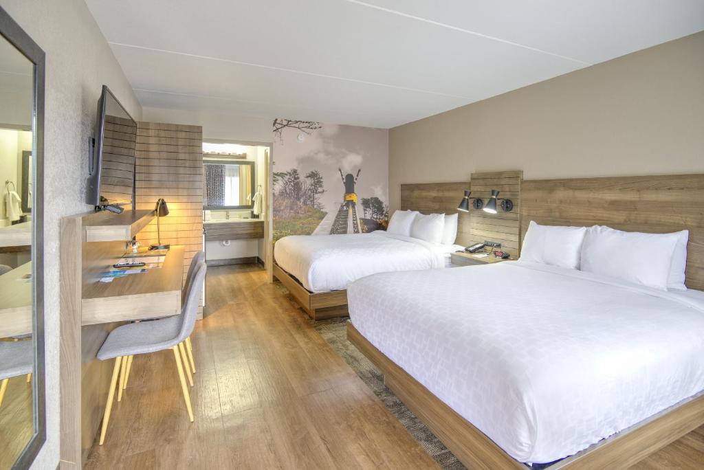 ein Hotelzimmer mit 2 Betten, einem Schreibtisch und einem Bad in der Unterkunft Clarion Pointe Downtown Gatlinburg in Gatlinburg