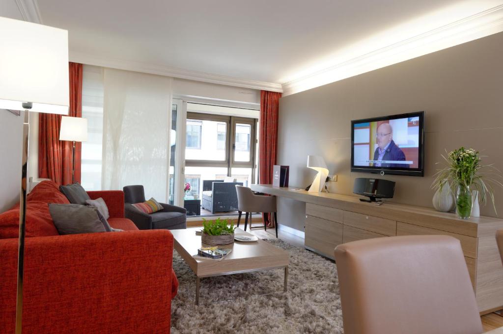 - un salon avec un canapé rouge et une télévision dans l'établissement Résidence Alma Marceau, à Paris