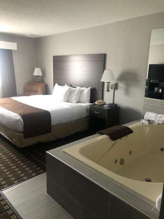 um quarto de hotel com uma cama e uma banheira em Adams Inn and Suites em Adams