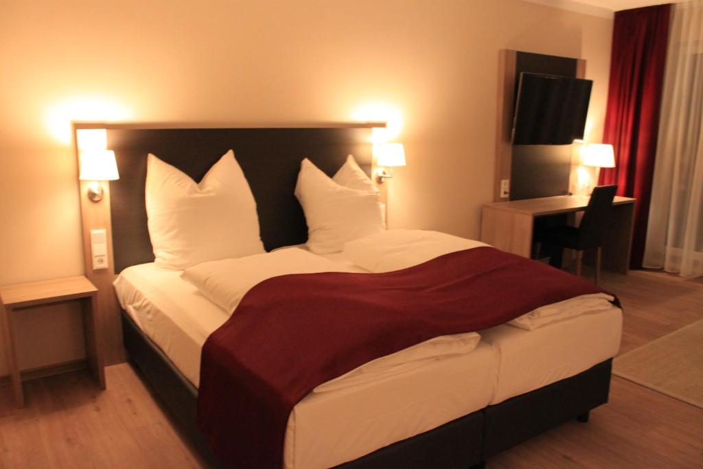 a bedroom with a large bed with white pillows at Troll's Brauhaushotel in Medebach