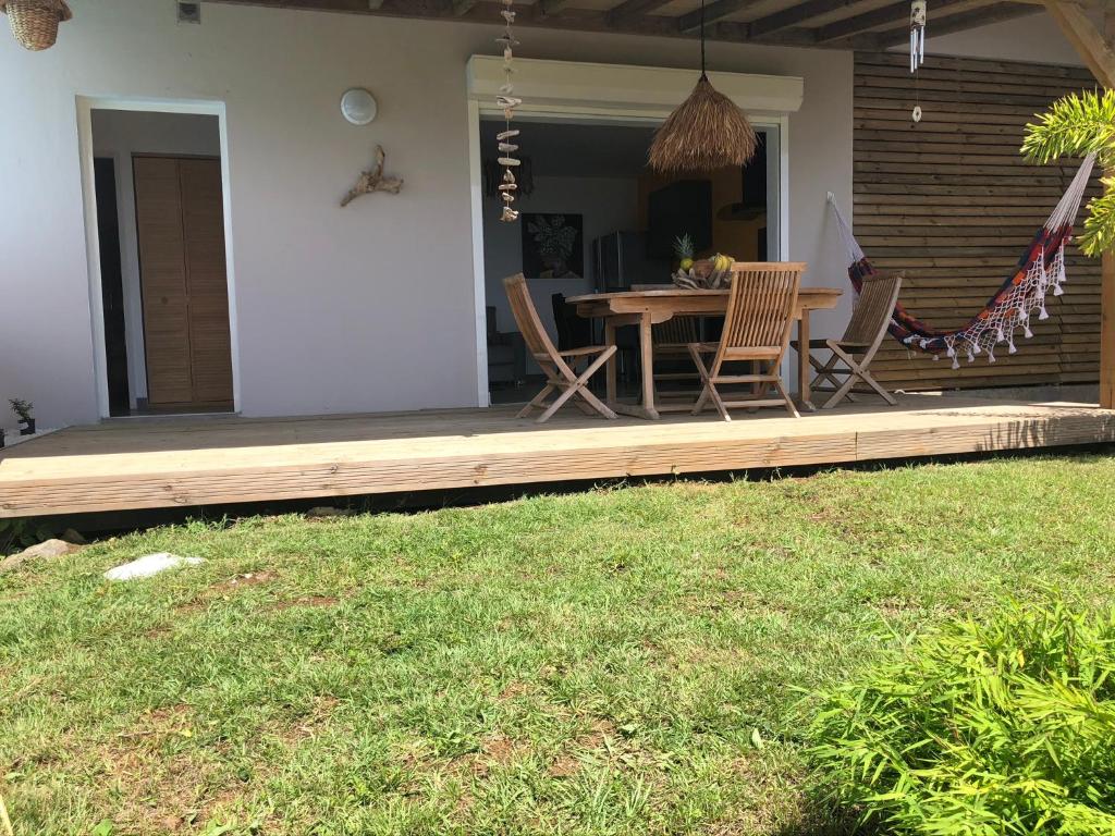 a wooden deck with a table and chairs on a house at Gîte Maracudja vue sur mer in Capesterre-Belle-Eau