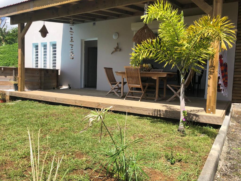 a house with a wooden deck with a table and chairs at Gîte Maracudja vue sur mer in Capesterre-Belle-Eau